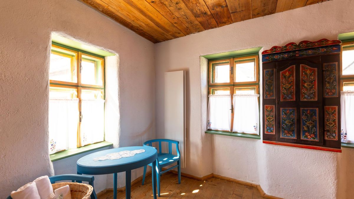 Painted armoire between the windows and a blue table with two chairs