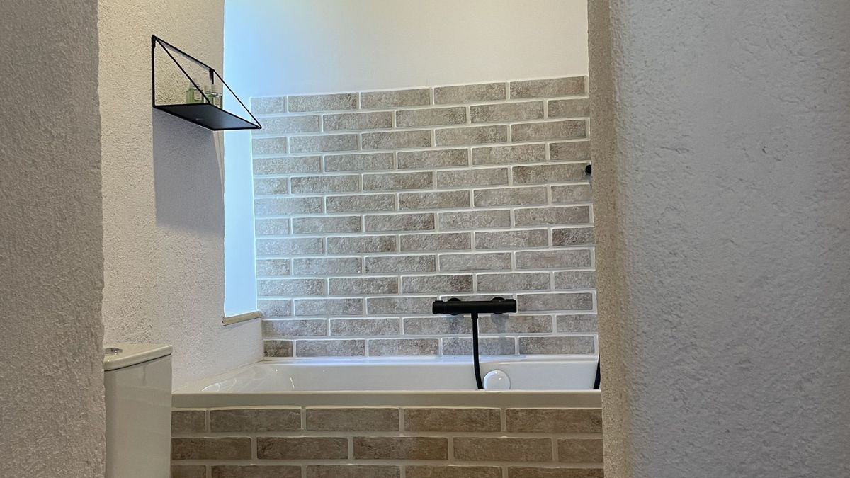 Bathroom with a bathtub set in pale brick