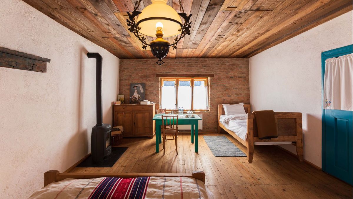The Family Room under its wooden ceiling, with the black stove and a single bed by the window