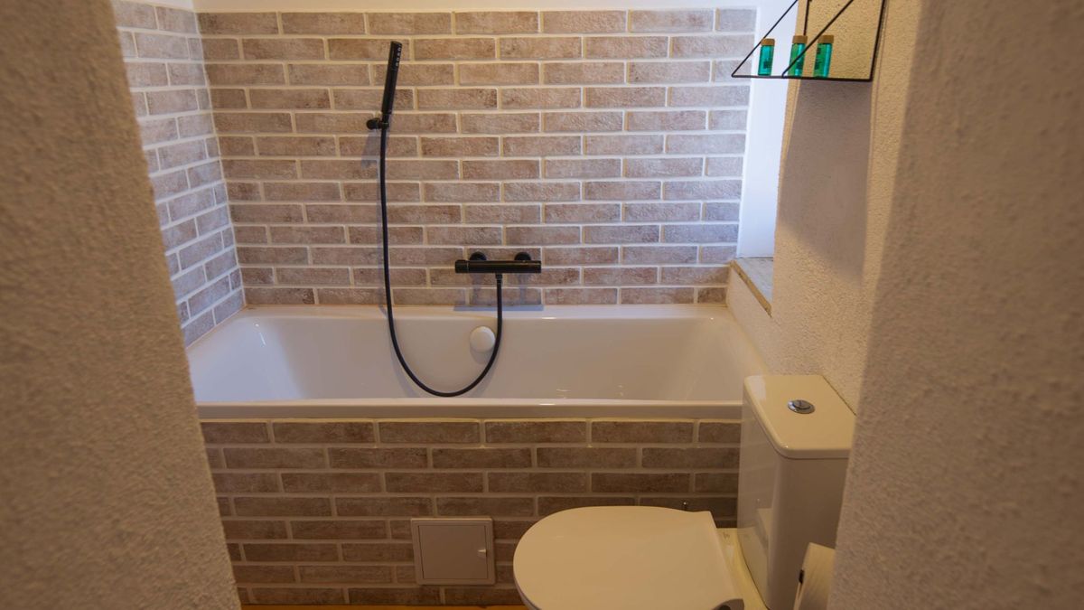 Bathroom with a bathtub set in pale brick