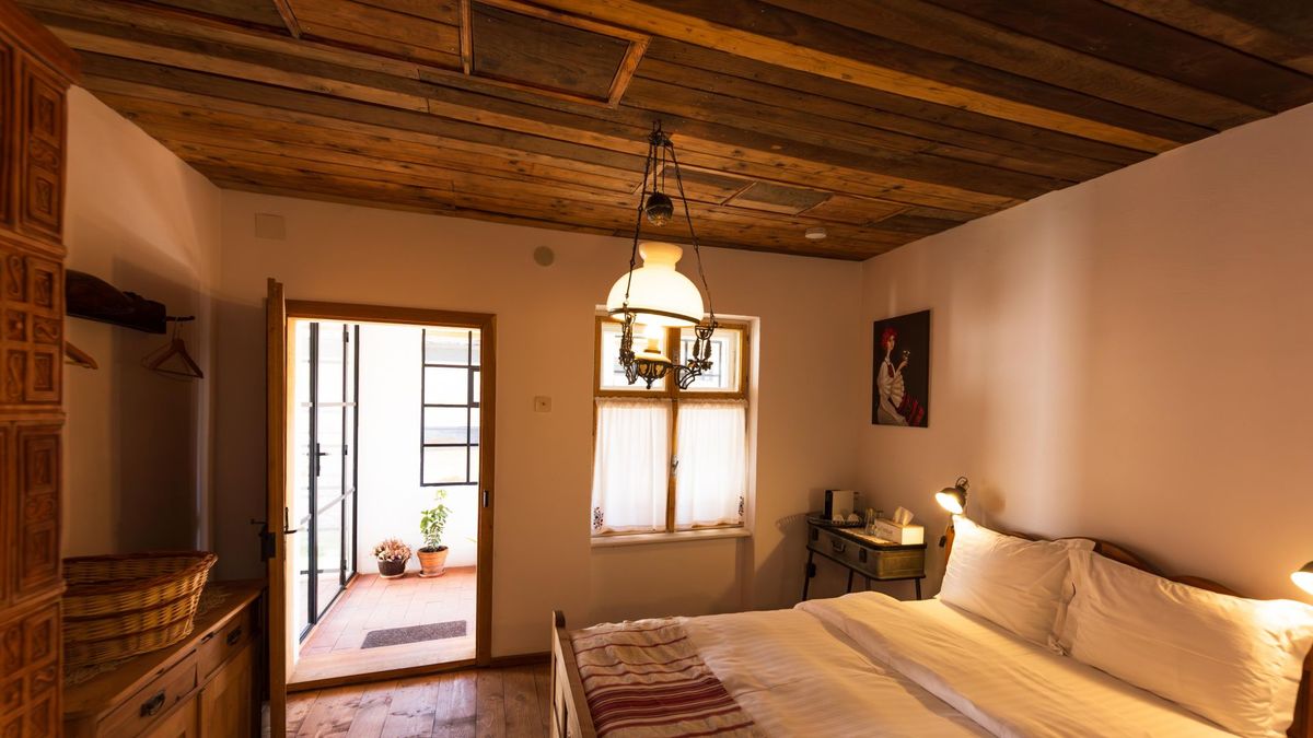 Bed under the wooden ceiling, the door open to the balcony
